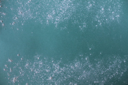 Background meal flour or powdered sugar scattered on a mint blue green background with a copypeist eat for text.の写真素材