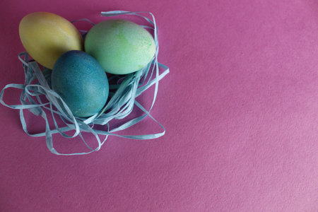 Easter background three multicolored eggs are candy next to a pink background with room for text...