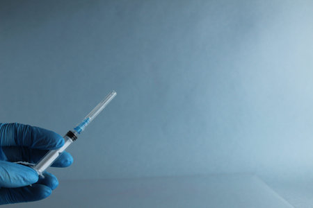 hand in blue medical glove holds apula or syringe vaccination vaccination with room for text copyspace.の写真素材