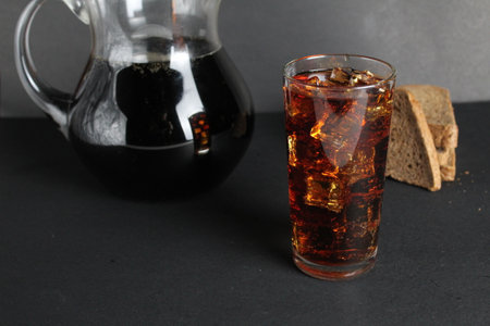 Dark bread kvass poured into a glass with solder and stands on a gray black background with a place for text and copyspace.の写真素材