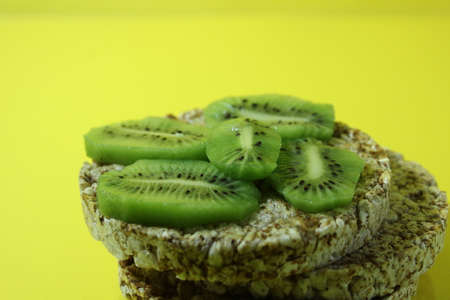 Healthy food breads with kiwi fruit on a bright yellow background with a place for text and copyspace.の写真素材