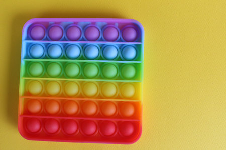 The toy anti-stress popit simple dimple view from above on a yellow background with a place for text...