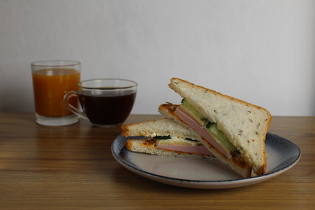 Breakfast snack lunch sandwich with sausage ham cheese cucumber lies on a plate next to a cup of tea or coffee. Morning serve. preparation. Cafe Restaurant.の写真素材