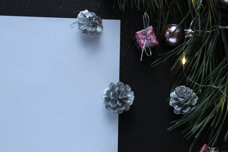 a white sheet of paper next to a branch of its pine tree next to a garland cone with space for text...