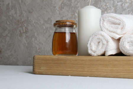 oil for body massage white candle towels snail on a wooden tray on a gray background side view. Spa relaxation massage. Body care.の写真素材