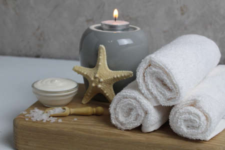 salt for bath massage peeling spa relax massage. Home salon body care. Beauty. White towels starfish salt candles on a wooden tray on a gray background side view.の写真素材