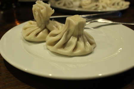 two khinkals lie on a white plate next to the fork and knife. National dish of Georgia.の写真素材