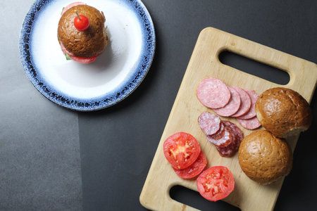 cooking a sandwich vegetables and sausage bun rye lie on a board tray made of wood on a black...