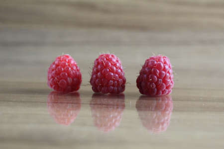 three close-up raspberries lie on a wooden background. Berries Vitamins Benefits.の写真素材