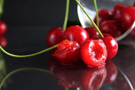 still life cherry berries fell out of the glass on a black background. Season berries vitamins side...
