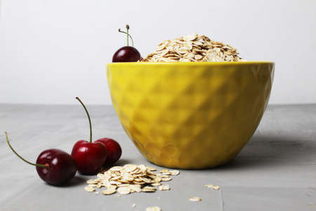 oatmeal oatmeal in a yellow plate bowl with cherry berries on a gray background. Proper healthy nutrition diet. delicious food.の写真素材