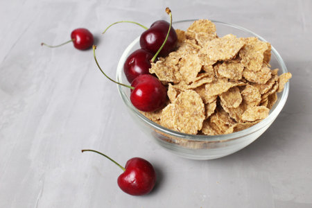 corn flakes with berries fruit cherries in a bowl plate on a gray background top view. Delicious...