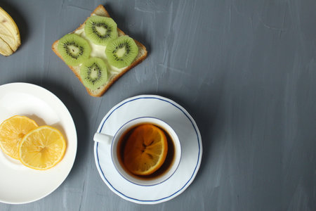breakfast with sandwiches tea with lemon sandwich with kiwi fruit on a gray background with space for copyspace text. Healthy food breakfast snack tea break.の写真素材