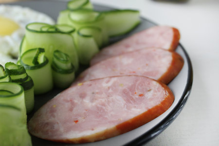 ham sausage with cucumber salot and barley on a gray plate. breakfast healthy hearty delicious food nutritious.の写真素材