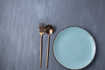 settable. Spoon fork and plate stands on a gray background with a place for food and text copyspace.の写真素材