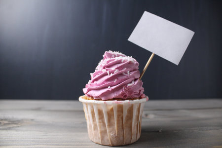 Cupcake with pink cream in the style with a sign for text copyspace mockup on a black dark background. Anniversary, celebration, celebration, congratulations on the holiday. Sweet Pie Day.の写真素材