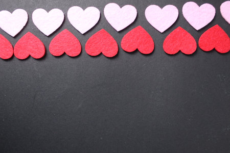 Red and pink hearts on a black dark background with space for text. Copy Space Valentine's Day. Festive background.の写真素材