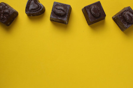 Chocolates lie on a yellow background with space for copyspace text. Background with chocolate.の写真素材