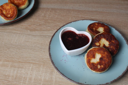 festive breakfast for Valentine's Day pancakes cheesecakes in plate with gravy boats heart shaped jam on the table with place for the text congratulationsの写真素材