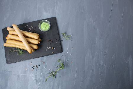Chicken sausages on gray background with basil and rosemary green pesto wasabi sauce on gray stone black background with space dls text copyspace. Cooking meat sausage products at home. Preparing for the barbecue.の写真素材