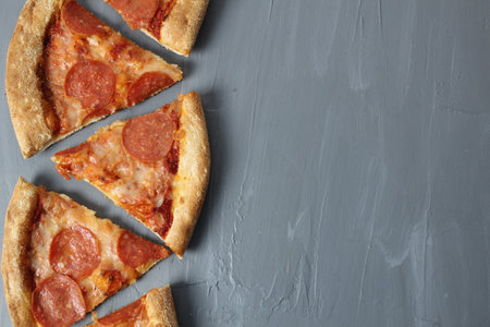 Border of pepperoni slices of pizza with cheese and sausage on a gray background with space for text Copyspace Upper angle.の写真素材