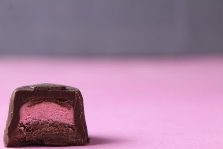 A piece of candy on a pink background with berry filling: strawberry, raspberry, mango.の写真素材