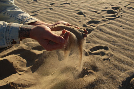 pours sand from his hands. Manual sifting of sand. Horizontal Photo.の写真素材