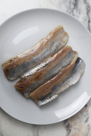 Pieces of herring fillet on a plate View from above. Preparation of fish dishes. horizontal photo.
