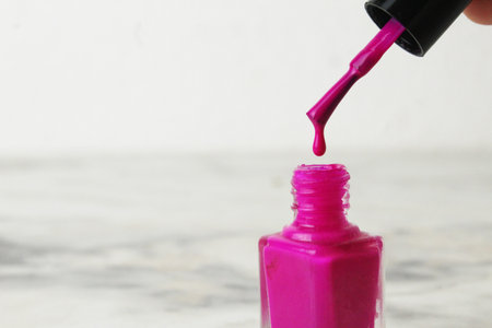 A drop of nail polish dripping from a brush close-up on a white background with space for copyspace text.の写真素材