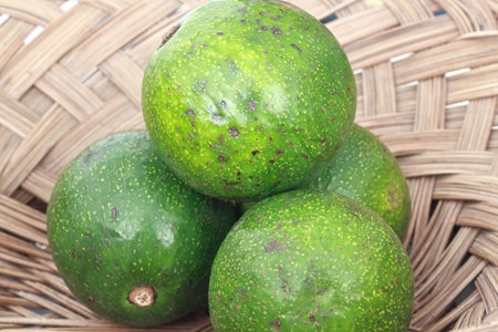 Avocado fruit in a wicker basket on a white background.