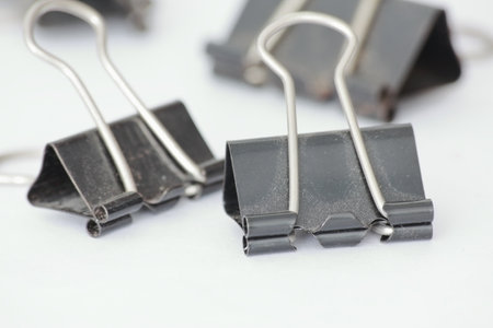 Close up of black paper clips on white background. Selective focus.の写真素材