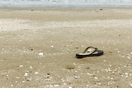 Junk on the beach.old slipper on sandの写真素材