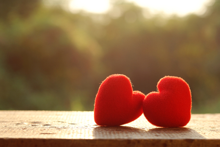 Two red pillow heart shape on wooden plate with sunlight, valentine day conceptの写真素材