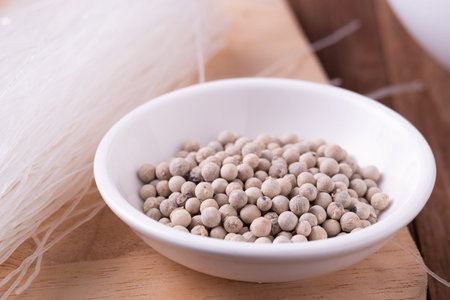 white Pepper seeds in white bowl on chopper board background