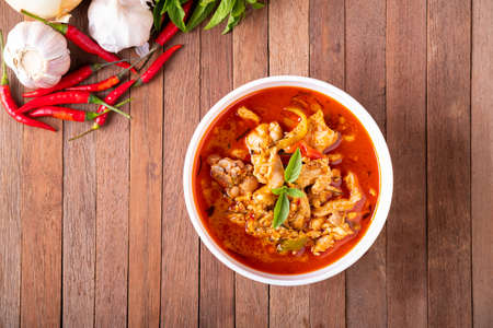 Thai curry red soup,Thailand tradition menu,boiled red curry with coconut milk and chicken on wood table.Top viewの写真素材