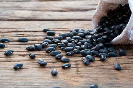 Heap of raw black bean in the sack on wood plate