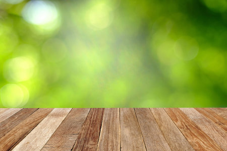 Wooden table with blur green leave background.perspective view for display products.