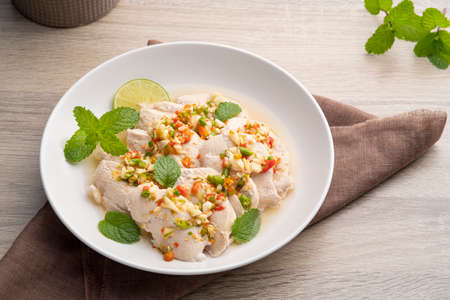 Thai hot and spicy food, Steamed sliced chicken breast in lemon sauce on white plateの写真素材