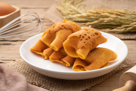 Pancake rolls stuffed with custard and sausage on white plate.popular street snack in Thailand call...