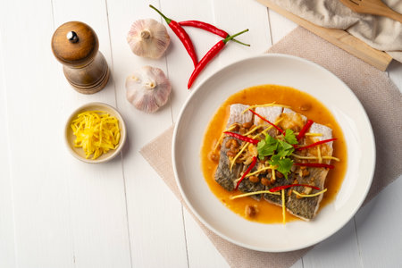Steamed Seabass fish with Soybean Paste sauce in white plate.Top viewの写真素材