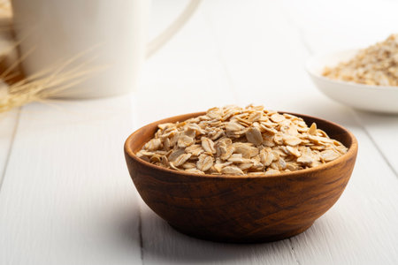 Oat flakes or rolled oats in wooden bowl on white plate.healthy eating, vegan food.