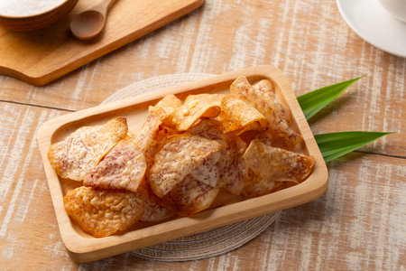 Crispy fried sliced taro with sugar,sweet taro chips in wooden plate.の写真素材