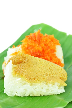 Traditional Thai dessert - sweet sticky rice top with steamed egg custard and minced coconut, shrimp on banana leafの写真素材