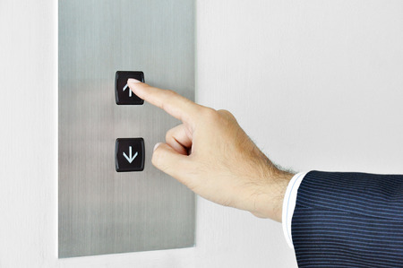 Businessman hand touching going up sign on lift control panelの写真素材