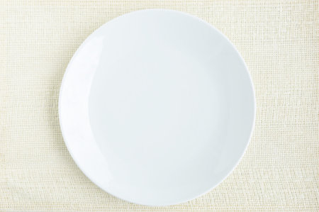 Empty white dish on cream fabric table matの写真素材