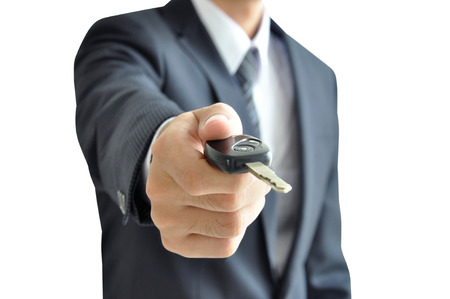 Businessman hand giving a car key - isolated on white backgroundの写真素材