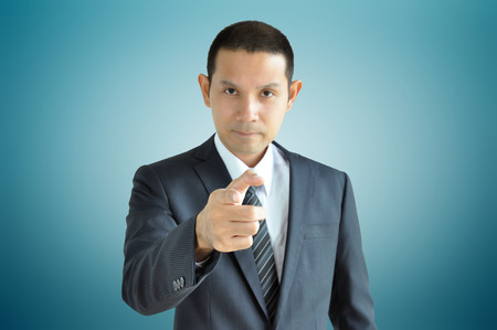 Asian businessman pointing finger at you with serious faceの写真素材