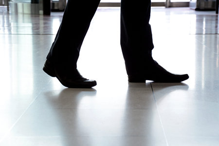 Businessman legs with black leather shoes walking on the floorの写真素材