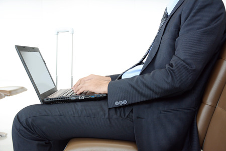 Businessman using laptop or notebook computer while sitting on the chair at the airportの写真素材