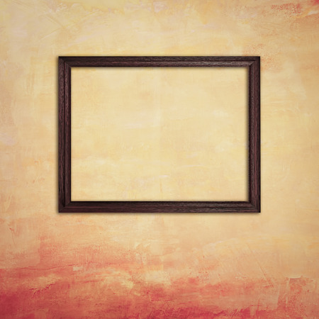 Wooden photo frame on old yellow concrete wallの写真素材